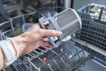 A dishwasher filter in a woman's hand. Soil removal.