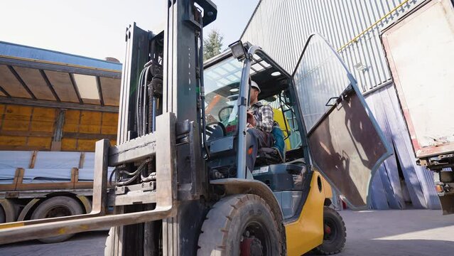 Male forklift driver working on loading and unloading goods in storehouse