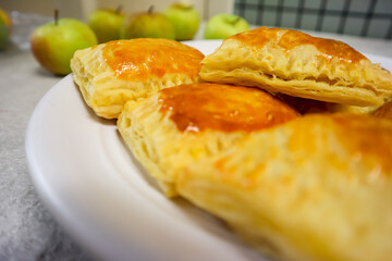 Homemade mini apple pie pastry placed on a plate with fresh apple in the background