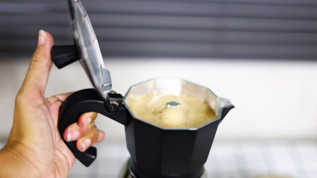 Manual moka Pot coffee maker while preparing to grind boiling coffee. Close up of coffee brewing in Italian espresso maker moka pot.