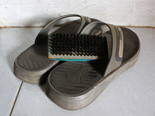 Close-up of a brush and sandals on the floor. 