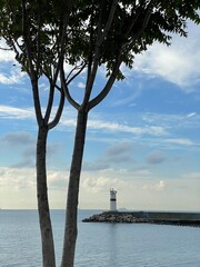 Fototapeta premium Lighthouse in the middle of the sea with trees and blue sky