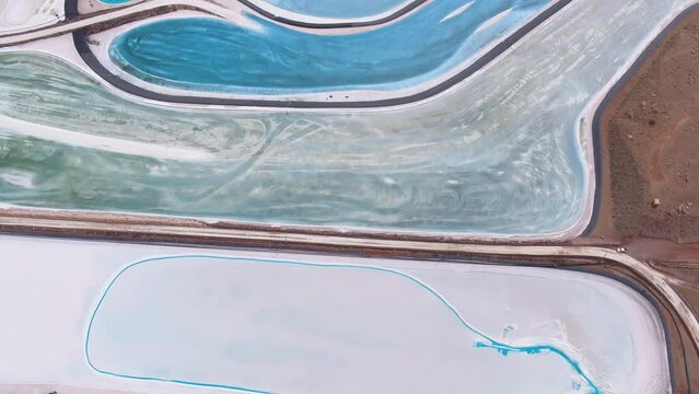 A spectacular 4K drone shot of the Potash Evaporation Ponds in Moab, Utah. The dazzling, electric blue water at this mining facility lies in stark contrast to the red desert landscape surrounding them
