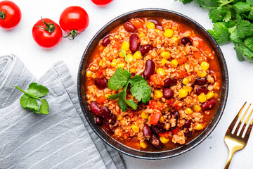 Chili con carne, mexican dish with minced beef, red beans, paprika, corn and hot peppers in spicy tomato sauce, tex-mex cuisine, white background, top view