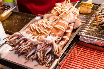 Stack of many grilled squid skewers on the grill in the Taiwan night market.