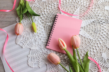 Spring mood: notepad with a bouquet of tulips on an openwork napkin - obrazy, fototapety, plakaty
