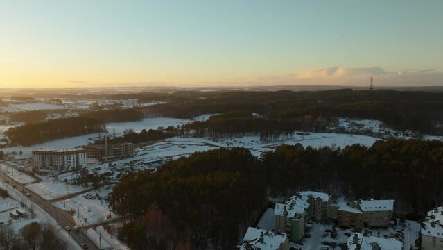 Aerial View Over Woodland Trees And Snow Covered Town Of Dabrowa In Gdynia During Golden Hour Sunset On Horizon. Push Forward Shot