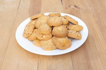 Bakery biscuits and cookies in white ceramic plate on wooden background