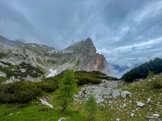 A hike though the Berchtesgaden Steinerne Meer by passing green and snow fields with rain clouds at...