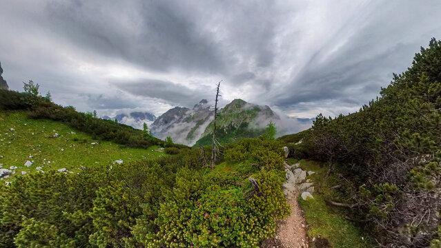 A hike though the Berchtesgaden landscape during summer with rain clouds and remaining snow fields