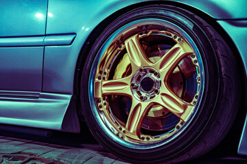 Close Up View of a Shiny Golden Alloy Wheel on a Blue Sports Car