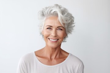 Cheerful mature lady looking at camera and smiling while standing against grey background