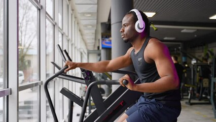 Fitness male using air bike for cardio workout at training gym