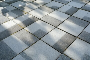 White and gray paving slabs with shadow of a tree on the ground