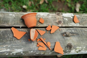 broken clay pitcher pieces on rustic wooden bench