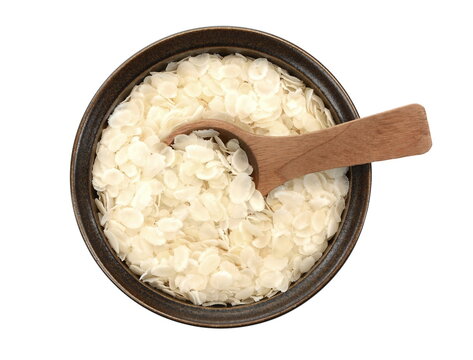 flattened rice flakes in a ceramic bowl isolated on white.