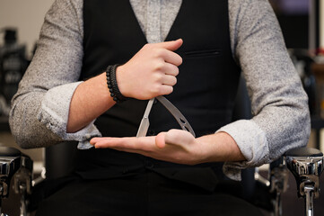 Closeup of a barber holding a dangerous razor in the shape of a triangle.