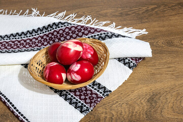 Traditional Romanian red Easter eggs decorated with leaves and boiled in onion peels on a wooden table