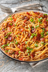 Cowboy Spaghetti with Ground beef, bacon, cheddar cheese, onion, pepper and tomatoes closeup on the plate on the table. Vertical