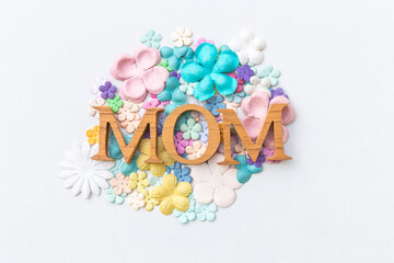 Mom wooden text on pastel color paper flower arrange in round shape on white background, mother's day card background idea