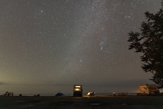 camper truck parked in front of ocean under the stars