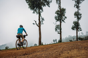 Mountain biker cycles along gravel road in the mountains of Rwanda