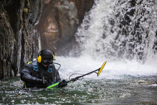 Suba diver adjusts his metal detecting equipment while in the water