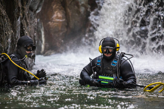 Team of divers use metal detecting equipment to find gold in a river