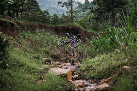 Man walks his bike across washed out cycling trail, Kibuye, Rwanda