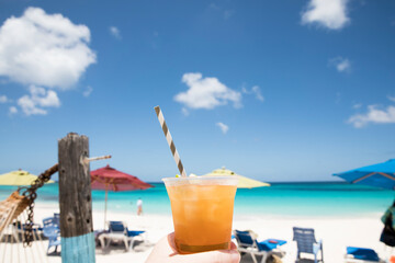 Tropical Drink With Striped Straw Held Up Against Blue Caribbean Sky