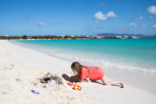 Wide Angle Side View of Girl Building Sandcastle on Caribbean Beach