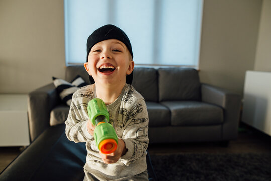 Close up of young boy laughing at camera while holding toy gun