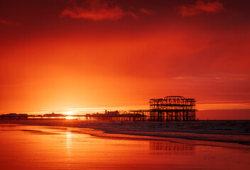 Brighton West  Pier and Palace Pier during a very vibrant red dawn on the east Sussex coast south...
