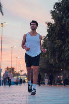 Man running through the streets of a city at sunset in sportswear