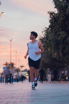 Man running through the streets of a city at sunset in sportswear