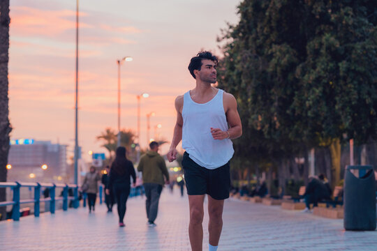 Man running through the streets of a city at sunset in sportswear