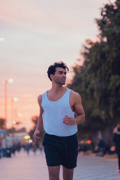 Man running through the streets of a city at sunset in sportswear
