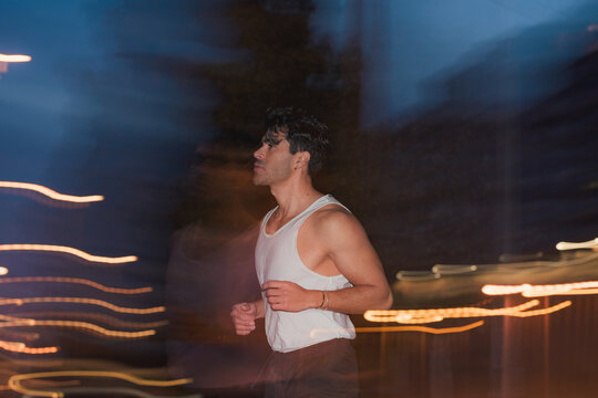 Athletic man jogging in tank top on city street