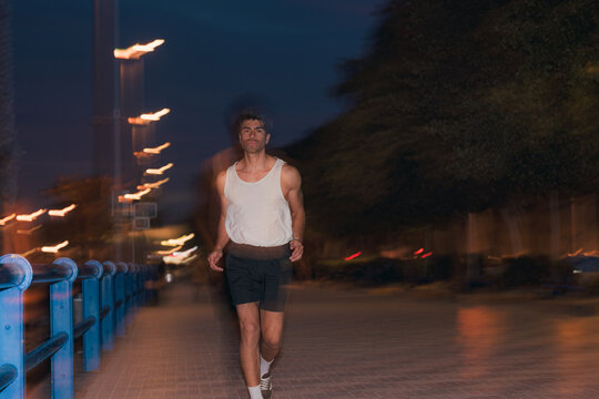 Athletic man jogging in tank top on city street