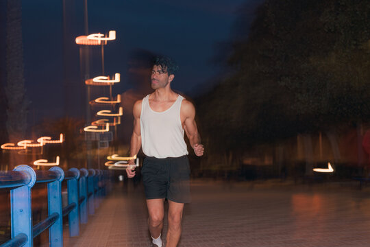 Athletic man jogging in tank top on city street