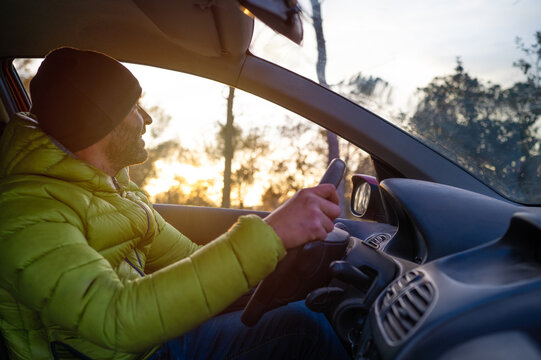 Mountaineer driving his car at sunset.