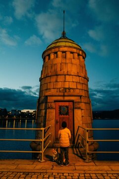 A boy and a dog stand on a bridge under the light of a lantern