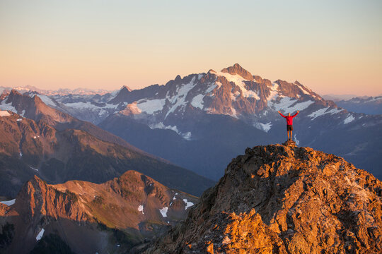 Hiker stands and raises arms on summit after successful hike