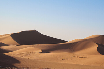 High desert sand dune two peoples on top in the distance