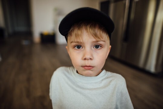 Portrait of young boy staring seriously at camera indoors at home