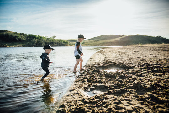Side view of two young boys playing in a lake on a summer evening.