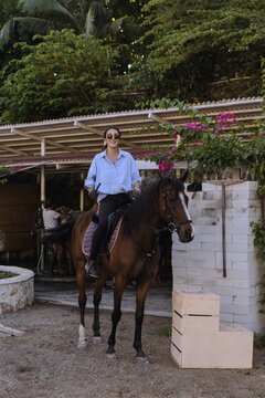 Young woman riding a horse at a riding school.