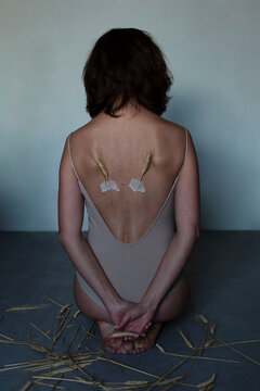 Girl sitting back with broken wings of wheat