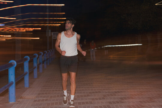 Athletic man jogging in tank top on city street