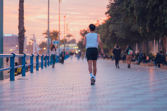 Man running through the streets of a city at sunset in sportswear